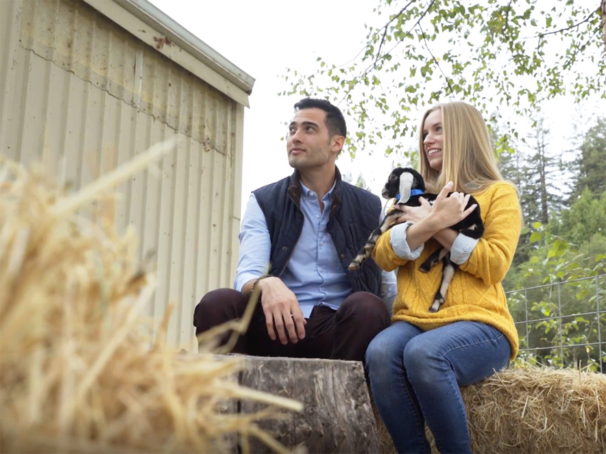 Two people cuddle a baby goat