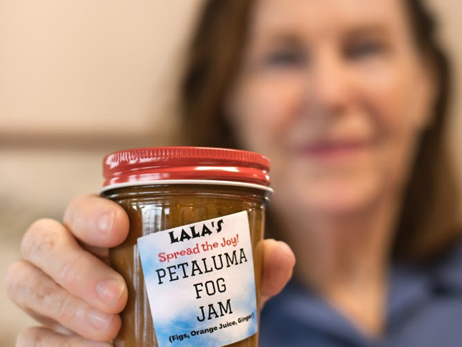 A woman holds a jar of jam that she made