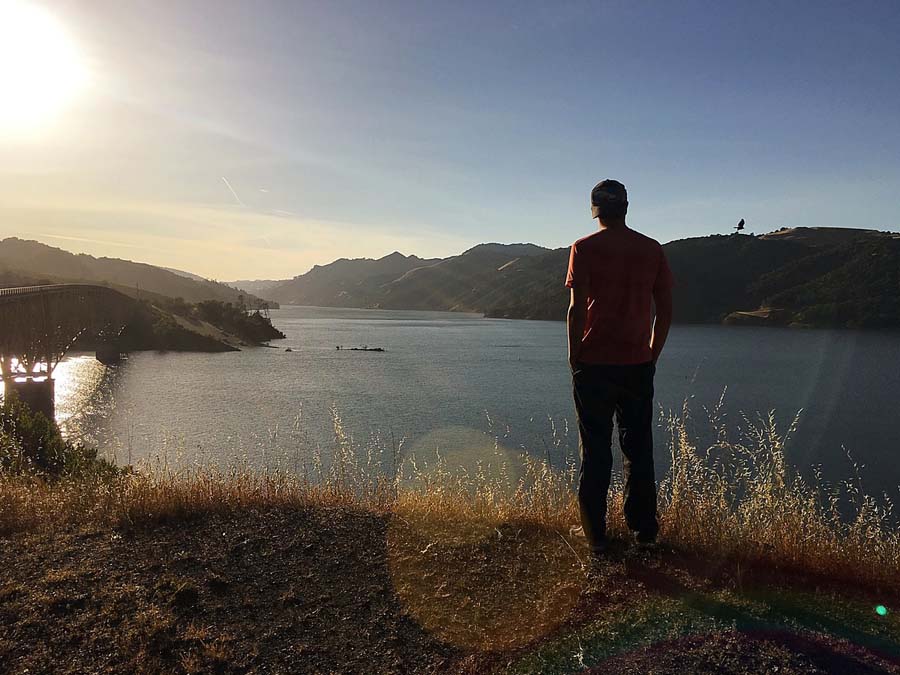 A person looks out over the setting sun on the lake