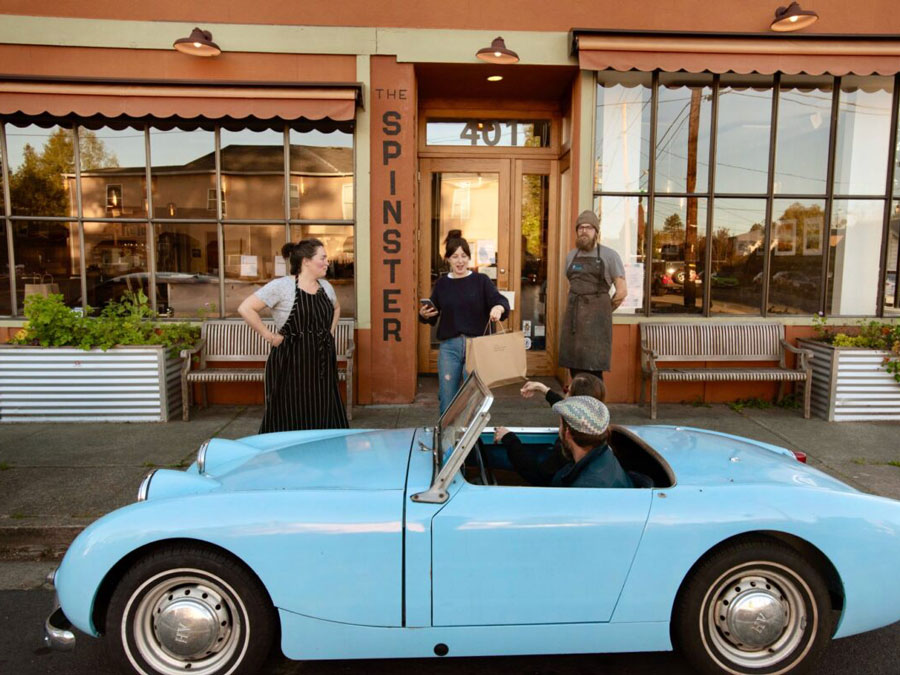 Outside of Spinster Sisters restaurant with a man being handed his order at his car.