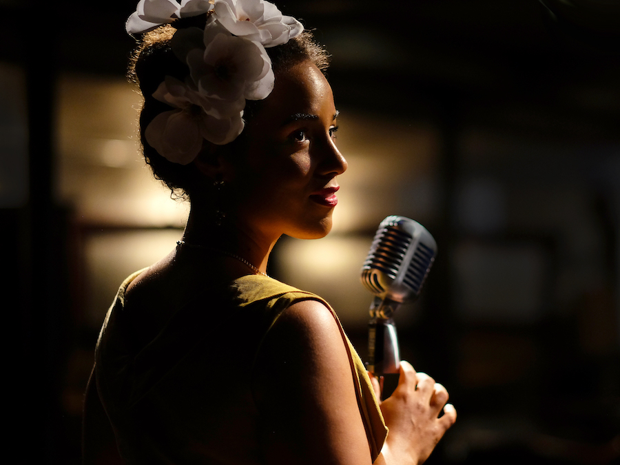 Picture of woman with a flower crown standing in front of mic on a stage