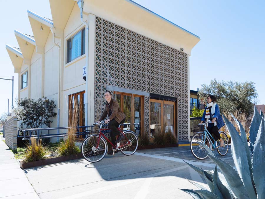 Two people on bike cruisers in front of the midcentury modern lodge