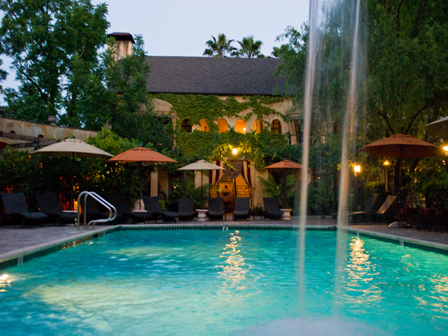 The glamorous outdoor swimming pool at Kenwood Inn and Spa is surrounded by vine-draped Spanish-Colonial architecture, fed by a fountain, and lit by twinkling lights