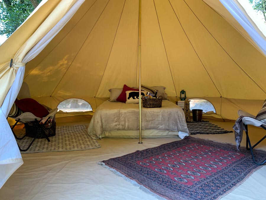 The interior of the luxury tent has rugs and a well-made bed in Sonoma County