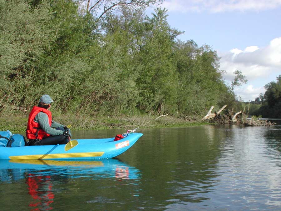 A person sits in a kayak on the river