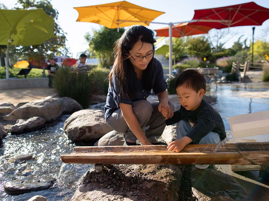 A young boy plays with the water feature outside at the Children's Museum of Sonoma County