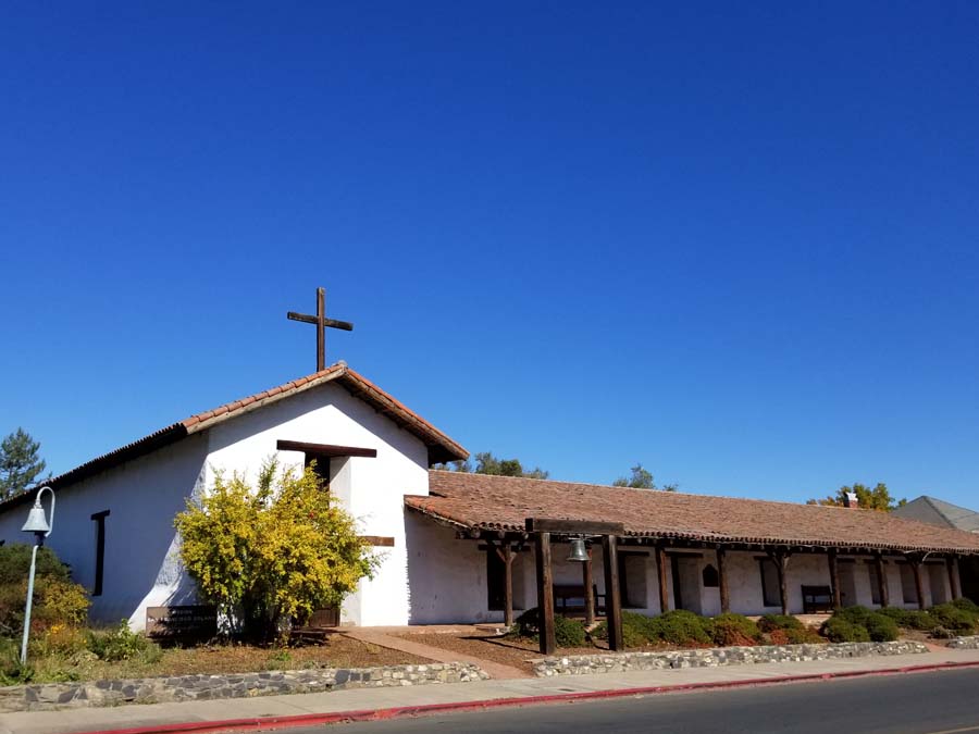 The white stucco mission has a wooden cross on top