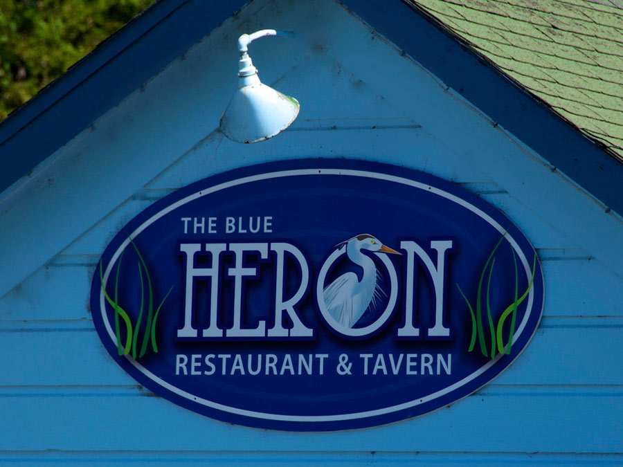 A sign for the Blue Heron restaurant on the blue building