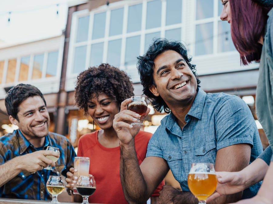 A group of friends drinks beer together outside on a patio