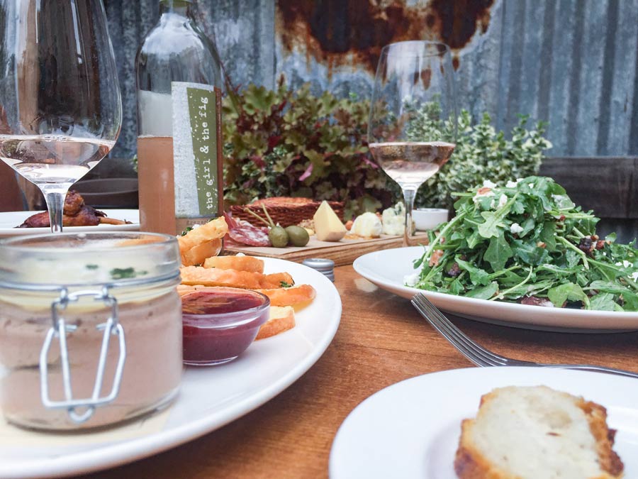 A table set outside with appetizers, salad, and wine