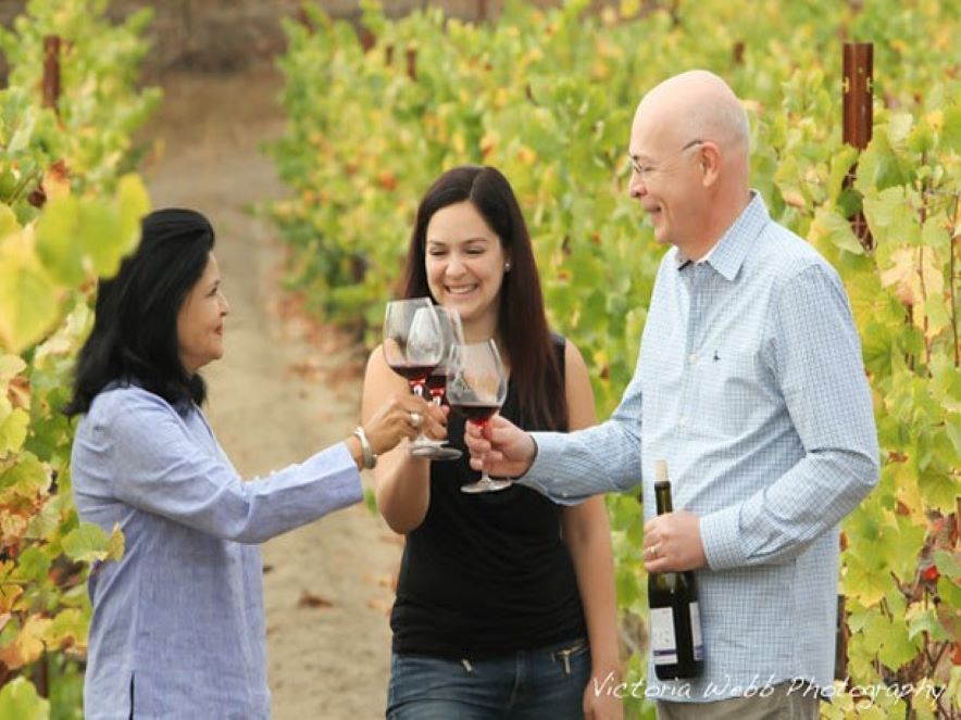 Picture of Enriquez family toasting glasses in vineyard