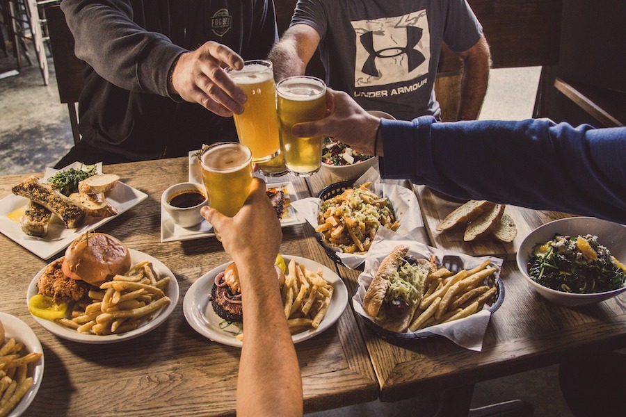 People toasting beers around a table laden with food at Fogbelt Brewing Company 