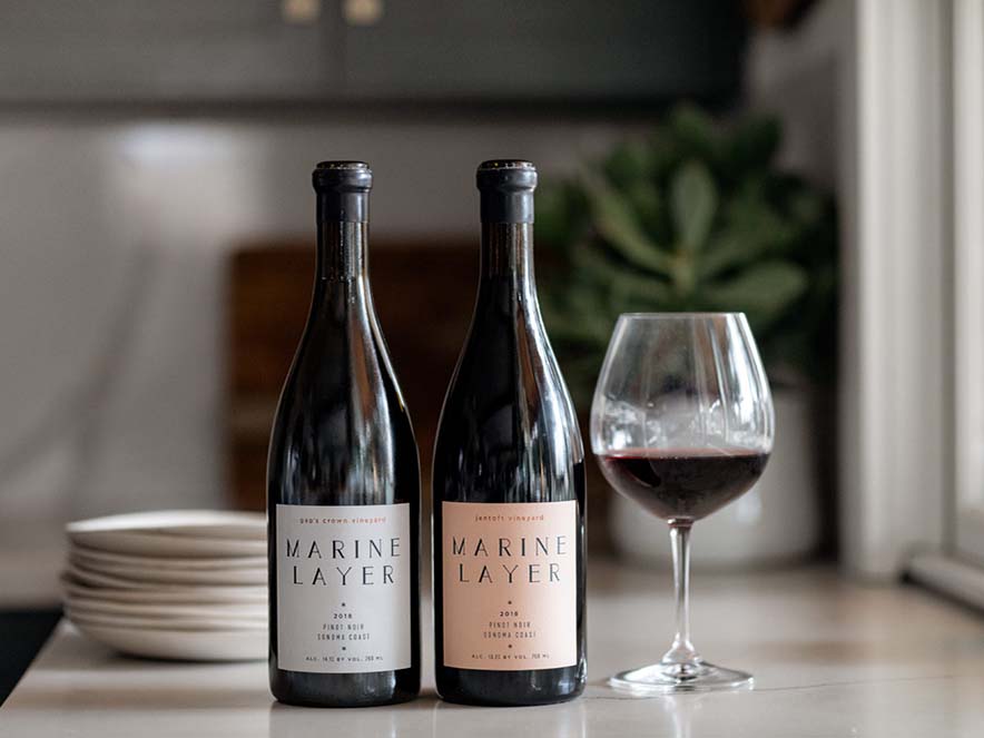 two bottles of marine layer wines with a glass of wine