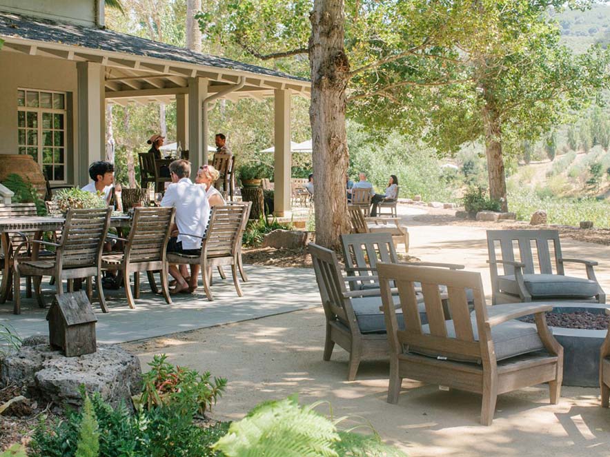 outdoor patio with people eating at tables and chairs around fire pit