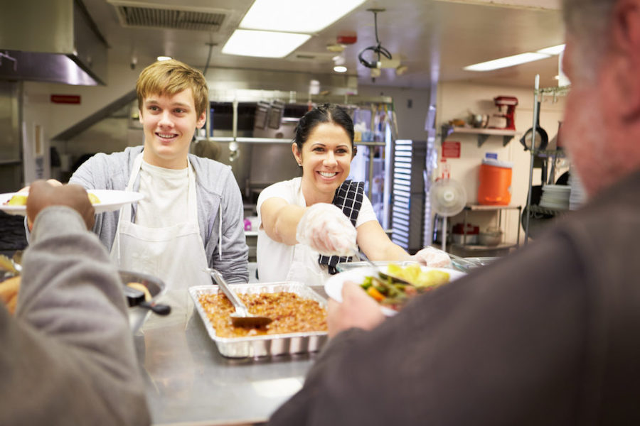 A young man and woman serving food at a shelter 