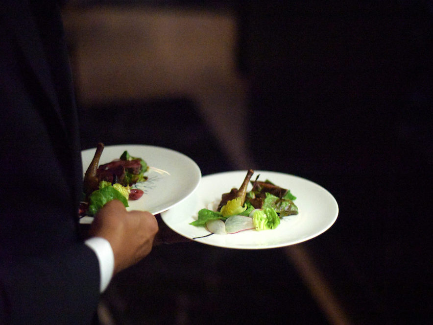 Gourmet dishes on white china in a waiter's hand 