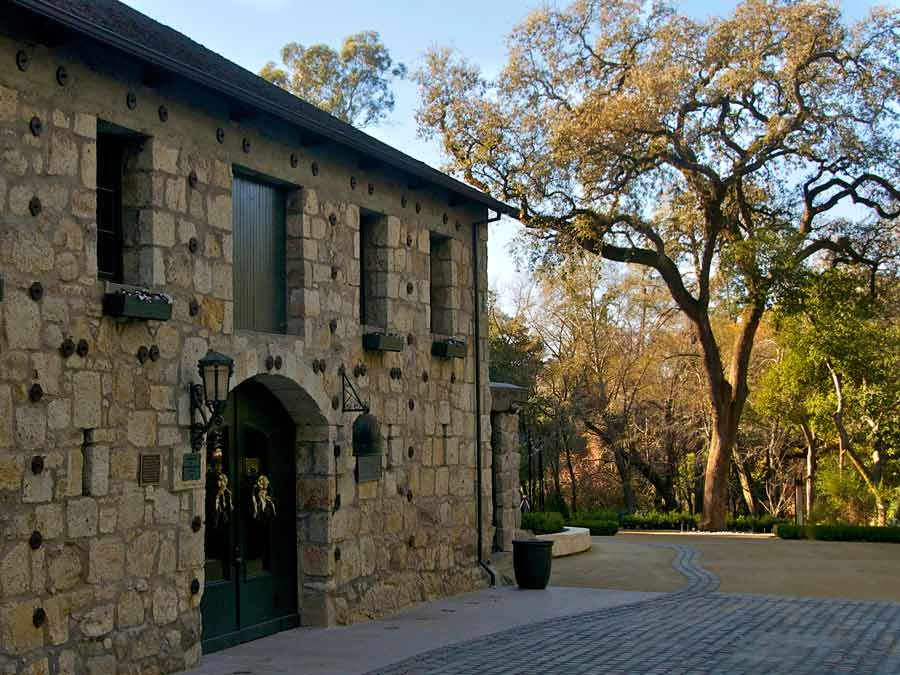 The old stone building has an oak tree growing next to it