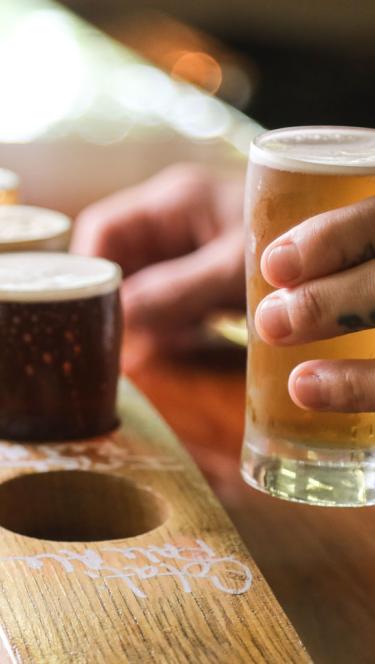 A person lifts a tester of beer from a board