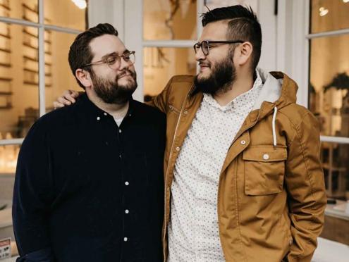 two men standing in front of white storefront